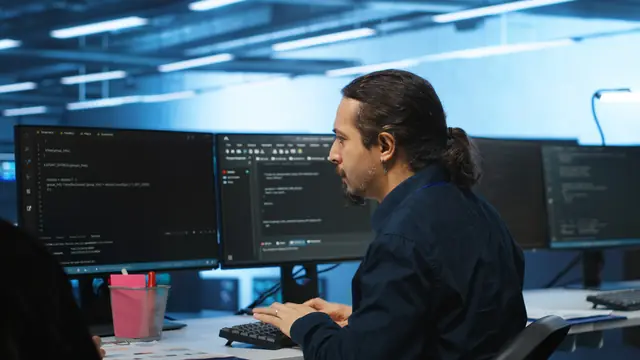 Software engineer working across multiple monitors in a delivery centre